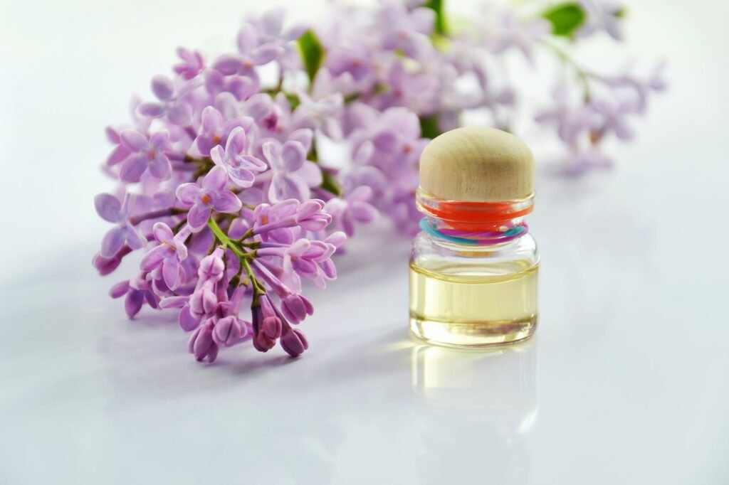 purple flowers beside a clear glass bottle with oil